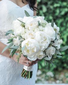 a bride holding a bouquet of white flowers