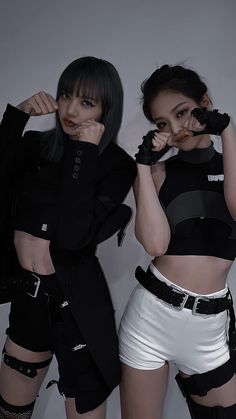 two women in black and white outfits posing for the camera with their hands on their hipss