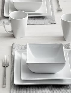 a table set with white dishes and silverware