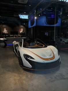 a white and orange sports car on display in a building