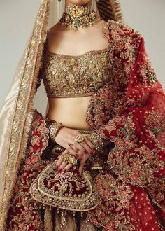 a woman in a red and gold bridal outfit with jewelry on her head,