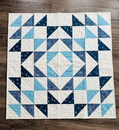 a blue and white quilt on top of a wooden floor