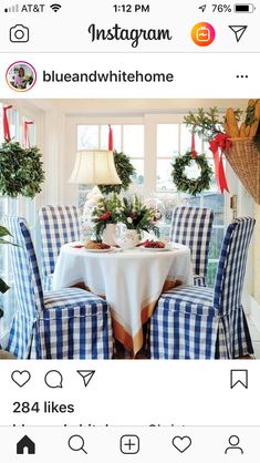 a dining room table with blue and white checkered chairs, wreaths hanging from the ceiling