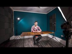 a man sitting at a table in front of a camera set up for a photo shoot