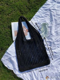 a black handbag sitting on top of a white blanket next to a magazine and water bottle