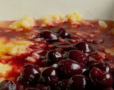 a close up of a plate of food with cherries on it and sauce in the middle