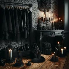 a black cat sitting on the floor in front of a fireplace with candles and clothes