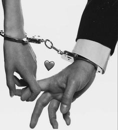 black and white photograph of two people holding hands with chains attached to each other,