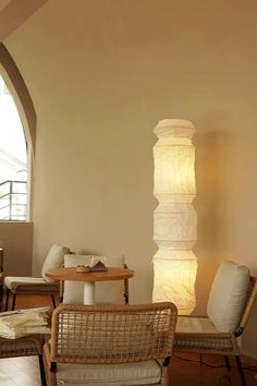 a living room filled with furniture next to a tall white vase on top of a wooden table