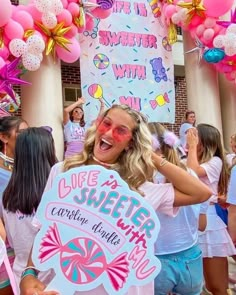 a group of women standing next to each other in front of a building with balloons and streamers