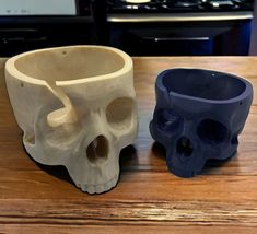 two ceramic skull cups sitting on top of a wooden table next to each other in front of an oven