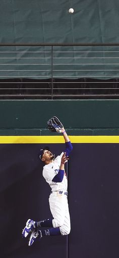 a baseball player catching a ball in the air with his glove and mitt out