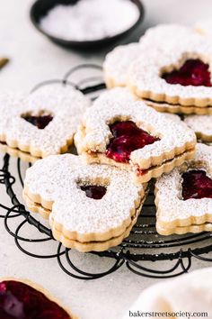 some cookies with jam on them are sitting on a wire rack and ready to be eaten