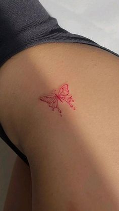 a red butterfly tattoo on the back of a woman's left arm and shoulder