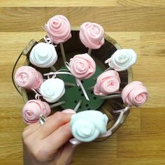 a person is decorating cupcakes with pink and white icing on sticks