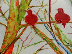 two red birds sitting on top of a tree next to each other in the branches