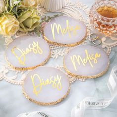 three personalized glass coasters sitting on top of a lace doily next to flowers