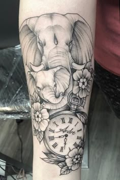 an elephant with flowers around its neck and clock on it's arm is shown