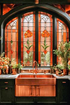 a copper sink in front of a large window with stained glass panels and flowers on the counter