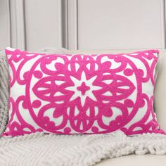 a pink and white pillow sitting on top of a couch