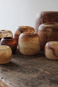 several vases sitting on top of a wooden table next to each other with different shapes and sizes