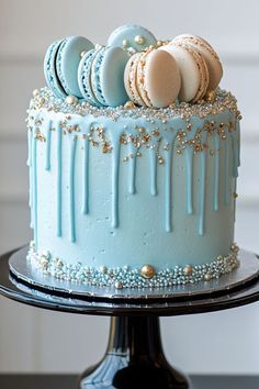 a blue cake with white frosting and macaroons on top, sitting on a black stand