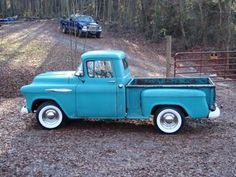 an old blue pickup truck parked in the woods