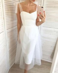 a woman in a white dress taking a selfie