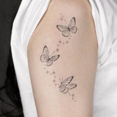 three butterflies flying in the air with stars on their wings tattoo design for women's upper arm