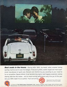 an old photo of two people in a convertible car watching a movie on the screen