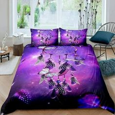 a bed covered in purple and black bedspread with two birds on the tree