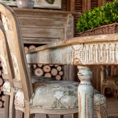 an old wooden table and chair with a basket on it's back end in front of a fireplace