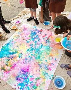 children are painting on the ground with their hands