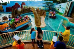 several people standing in front of a painting on the side of a roller coaster at an amusement park