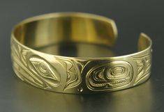 This is a new, hand-engraved, Northwest Coast Native First Nations gold cuff bracelet. Depicting Raven and Frog, this exquisitely carved gold bracelet measures 1/2" x 6" and will fit a wrist between 6 1/4" - 6 3/4" in circumference. It is signed on the inside by Kelvin Thompson and weighs roughly 18 grams solid 14k gold.Raven is often paired with Frog in Native art from the Pacific Northwest because Frog is viewed as the one who communicated Raven's knowledge to the people. These symbols also re Carved Symbolic Yellow Gold Jewelry, Yellow Gold Symbolic Carved Jewelry, Adjustable Yellow Gold Hallmarked Cuff Bracelet, Heirloom Yellow Gold Cuff Bracelet For Ceremonial Occasions, Ceremonial Gold Bracelets With Polished Finish, Ceremonial Heirloom Yellow Gold Cuff Bracelet, Symbolic Gold Intaglio Jewelry, Luxury Engraved Round Cuff Bracelet, Symbolic Carved Gold Jewelry