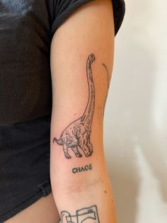 a woman with a tattoo on her arm that says chaos and an image of a dinosaur