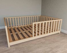 a wooden bed frame sitting on top of a hard wood floor next to a wall