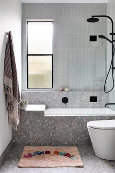 a bath room with a toilet a tub and a shower head mounted to the wall