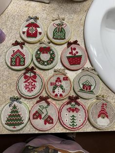 cross - stitch christmas ornaments are arranged on the counter next to a sink and toilet