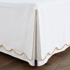 a bed with a white bedspread and gold trimmings on the edges