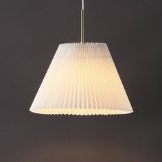 a white lamp hanging from the ceiling on a dark background with only one light attached to it