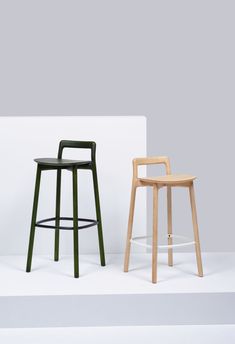 two stools sitting next to each other in front of a white wall and floor