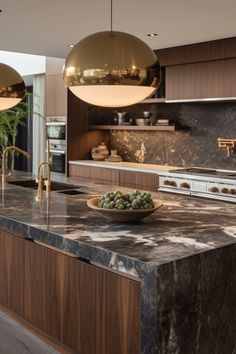 a large kitchen with marble counter tops and wooden cabinets, along with two hanging lights above the island