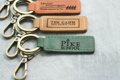 four different colored leather keychains with the words pike school written on one side