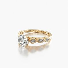 a gold engagement ring with three stones on the band and an oval shaped diamond in the center