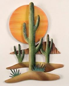 a cactus and some other plants on a white surface with an orange sun in the background