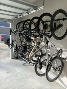 there are many bikes hanging on the wall in this storage area, and one bike is upside down