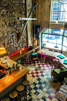 a room filled with lots of tables and chairs next to a wall covered in stone