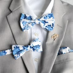 a man wearing a gray suit with blue and white flowers on his lapel bow tie