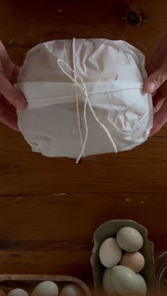 two hands holding a bag of eggs on top of a wooden table